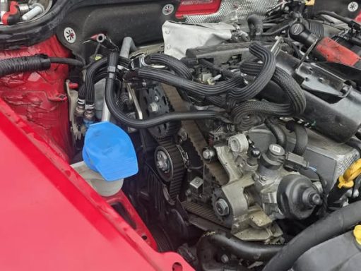 Close-up of an engine compartment with various components and a blue coolant reservoir.