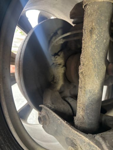 Close-up of a vehicle's wheel assembly showing brake components and dust accumulation.