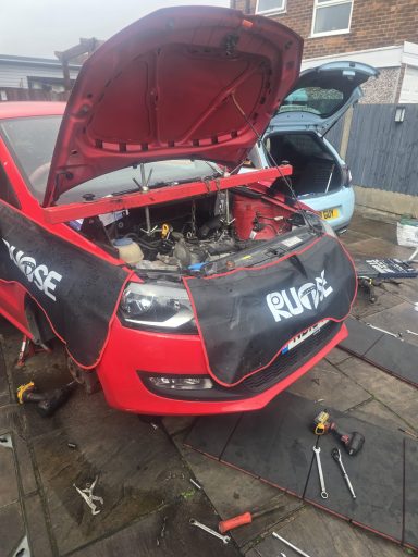 VW Polo with engine hoist and wing covers being worked on
