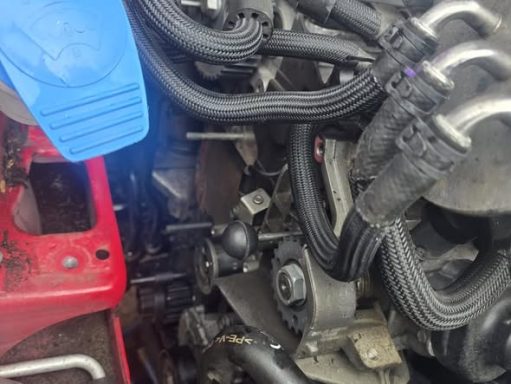 Close-up of a mechanical engine with hoses and components, featuring red and blue parts.