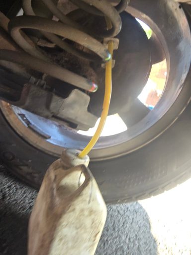 Yellow hose connected to a reservoir under a vehicle's suspension system.