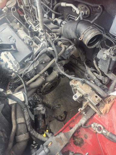 Exposed car engine with tangled wiring and components visible.
