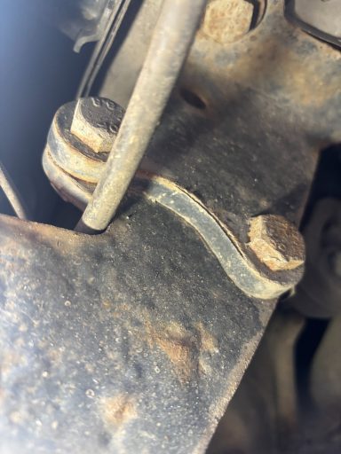 Close-up of a rusty metal bracket with a bolt and a rubber gasket.